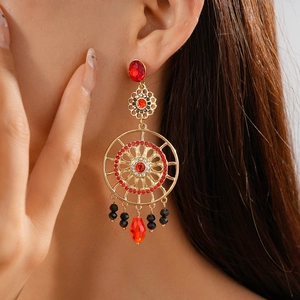 Close-up of model wearing vintage floral gold earrings with red and black crystals