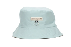 Close-up of light blue sun hat with beige 'How do you do?' patch and metal ring