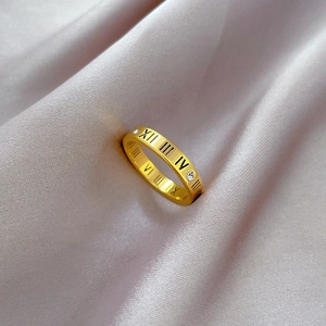 Detailed macro of gold-plated ring with engraved Roman numerals and inlaid zircon stones