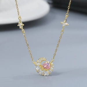 Detail of gold moon pendant featuring pink heart gemstone and sparkling star accents