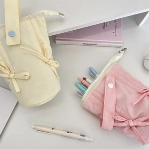 Macro detail of macaron pencil cases with ribbon bows and portable snap handles