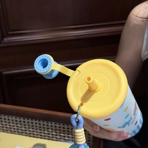 Detail of cute water bottle featuring a yellow lid, blue silicone straw, and woven lanyard