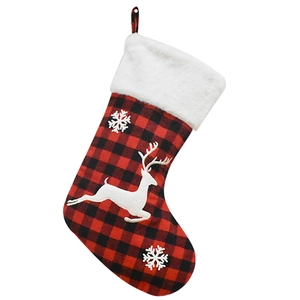 Detail of red and black plaid Christmas stocking with white reindeer and snowflake embroidery
