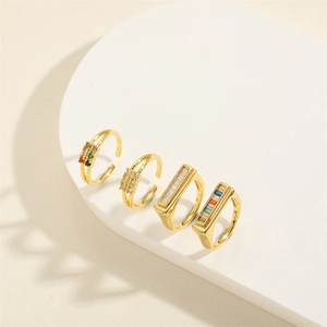 Set of four gold-toned rings with colorful zircons on a white minimalist display stand