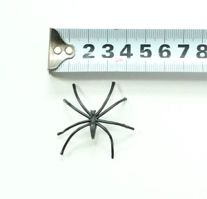 Detail view of 5cm small black plastic Halloween spider prop with measuring tape scale