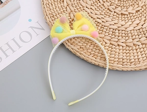 Close-up of yellow mesh headband decorated with colorful soft pom-poms for girls