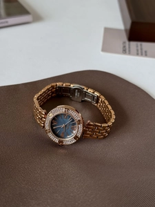 Detail view of rose gold steel clasp and luxury watch band on a leather cushion