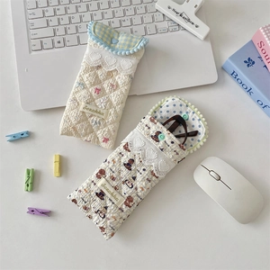 Detailed view of quilted cotton glasses cases with cute bow and bear patterns on a desk