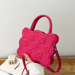 Detail of fuchsia pleated cloud bag with scalloped edges and textured square pattern
