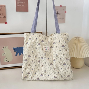 Detail of quilted canvas tote with cute rabbit prints and purple fabric handles