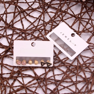 Close-up of pink, gold, and black stud earrings set on jewelry display cards