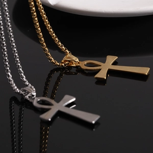 Polished gold and silver Ankh cross necklaces displayed on a black reflective surface