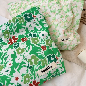 Detail of green floral and cream ditsy print cotton drawstring storage bags with woven label