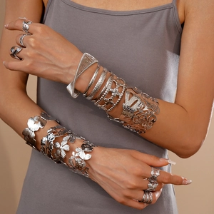 Detailed view of silver metal flower and ginkgo leaf open cuff bracelets on model