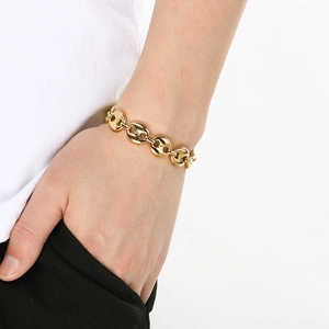 Detailed view of a gold coffee bean pig nose chain bracelet worn on a man's wrist