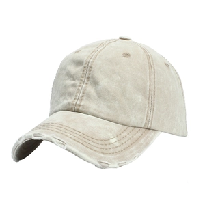 Close-up of distressed cotton baseball cap showing frayed brim details and beige twill texture