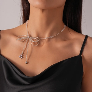 Detail of silver bow pendant necklace with glass beads on model wearing black silk