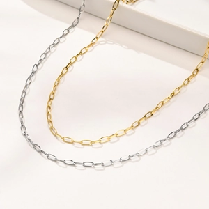 Minimalist gold and silver stainless steel paperclip chain necklaces set on white pedestal