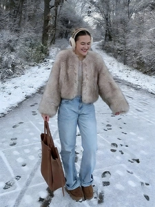 Short faux fur beige jacket worn in snow with jeans and brown boots for winter outfit
