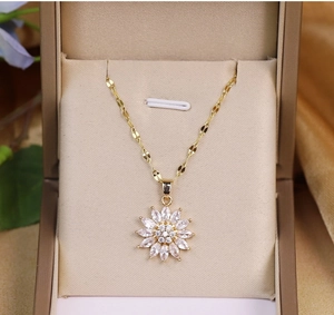 Detailed close-up of a gold-plated daisy flower pendant set in a beige jewelry gift box