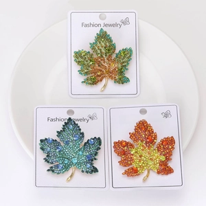 Detailed view of maple leaf brooches with colorful rhinestones in three gradient colors
