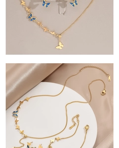 Detail of gold butterfly necklace with blue enamel accents on silk background