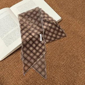 Close-up of vintage brown plaid silk scarf ribbon accessory on an open book