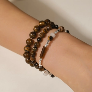 Close-up of layered beaded bracelet with tiger eye stone and obsidian on model's wrist