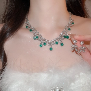 Detail of emerald necklace and bow earrings with crystals on soft white feathers