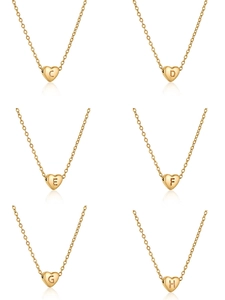 Détail de pendentifs coeur dorés avec diverses lettres gravées sur des chaînes fines