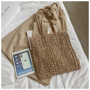 Detailed view of handmade straw woven tote with hollow flower pattern and brown straps