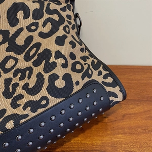 Close-up of leopard print canvas bag with silver rivets and black leather details