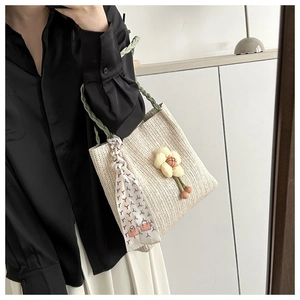 Detailed view of woven bucket bag with green handles and decorative silk scarf accessory