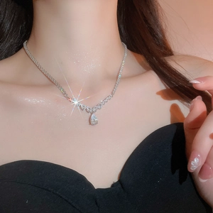 Detailed view of teardrop zircon pendant on shimmering silver tennis chain worn by a model