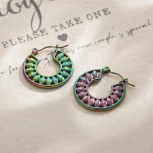 Macro detail of colorful hollow leaf pattern stainless steel earrings with iridescent finish