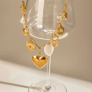 Détail du collier doré avec charms en perles et pendentif coeur gravé avec le mot Love