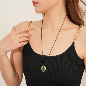 Vintage heart necklace with green gemstone on a golden base worn by a model