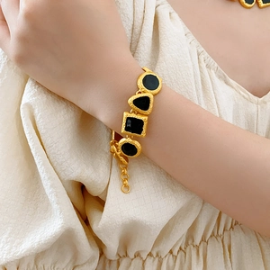 Close-up of vintage gold bracelet featuring geometric black stones on model wrist
