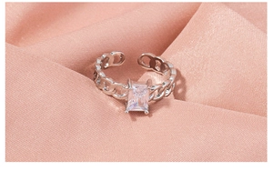 Macro detail of adjustable silver ring with rectangular zircon on silk background