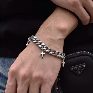 Close-up of silver steel Cuban chain bracelet with three cross charms on a model wrist