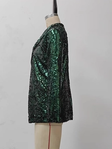 Detail shot of shimmering dark green sequins on the tailored sleeve of a blazer