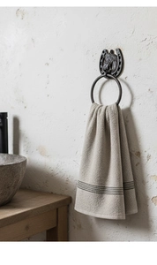 Detail of rustic cast iron horse head towel ring on a vintage textured wall