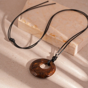 Macro view of vintage brown resin geometric pendant necklace with gold textured details