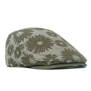 Detailed close-up of brown denim ivy cap featuring white daisy floral embroidery patterns