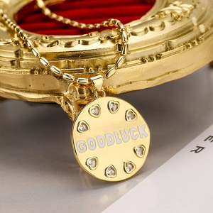 Collana con ciondolo tondo dorato, incisione GOOD LUCK e cristalli a cuore