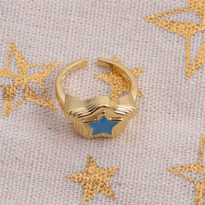 Detailed shot of gold layered star ring with blue enamel center on a textured background