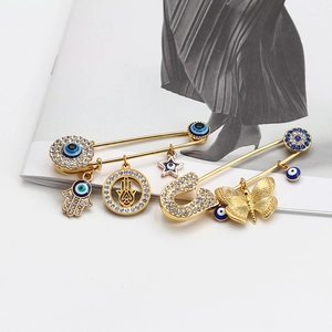 Golden Hamsa hand and Evil Eye safety pin brooches with sparkling blue crystals