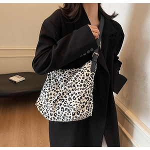 Detailed view of leopard print tote bag with black leather adjustable strap on model