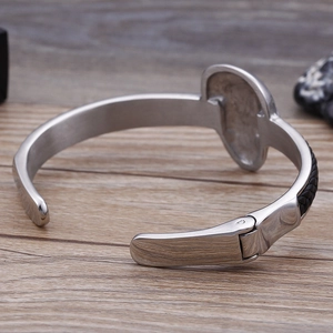 Detailaufnahme eines silbernen Edelstahl-Totenkopf-Armbands mit schwarzem Ledergeflecht und Scharnier