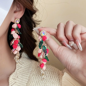 Détail de boucles d'oreilles vintage fleurs roses en résine avec pompons cristal